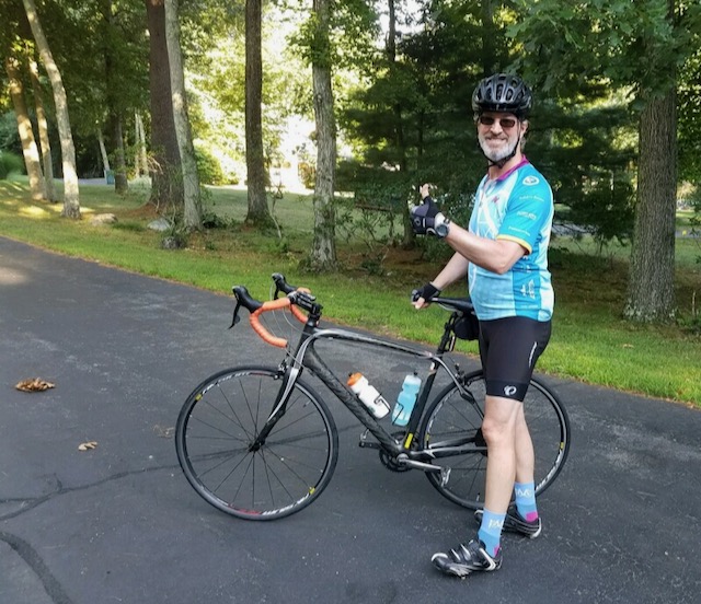 A young boy riding a bicycle on a road
Description automatically generated